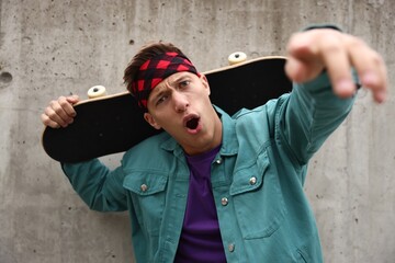 Stylish man with skateboard near grey wall outdoors © New Africa