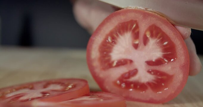 Macro wide close up of knife slicing and chopping a red tomato salad, food,