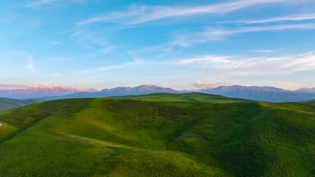 dolly forward drone hyperlapse above rolling green hills in Kyrgyzstan at summer evening
