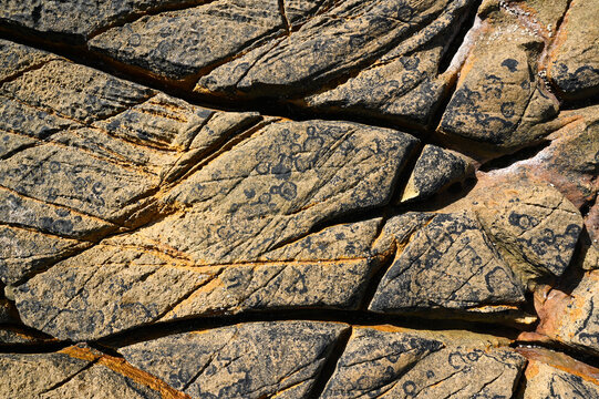 A granite rock formation on the Atlantic coast, with grooves and crevices carved out by the waves and seawater, weathered and eroded.