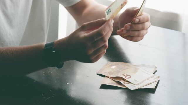 Person counting cash banknotes and dropping them on table with money rustling sound
