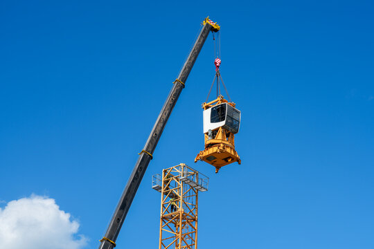 Mobile Crane Lifting Operator Cab onto Tower Crane Mast During Assembly at Construction Site