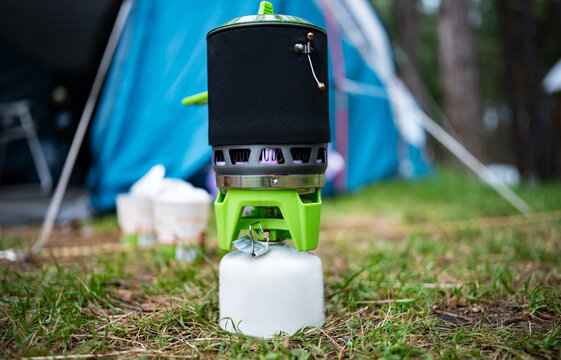 Camping Gas Stove With Small Canister Boils Water Near Tent At Campsite