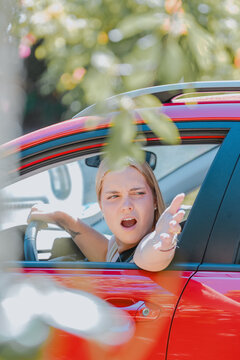 young woman driving angrily, protesting out the window, vertical