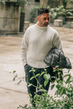 young man walking in the botanical garden with his jacket under his arm