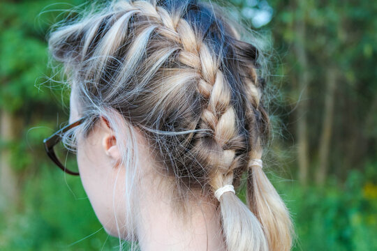Warsaw, Poland,May 15, 2026. Back view close-up of a young woman with braided hair wearing glasses outdoors in Warsaw. High quality photograph