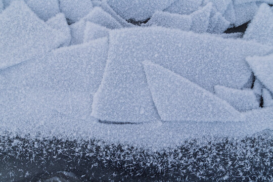 Close-up of frosty and snowy ice chunks on a frozen lake in Finland in winter, viewed from above. Abstract full frame textured wintry background. Copy space, top view.