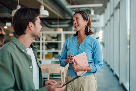 Business woman and man communicating in modern office hallway, discussing project and collaborating on work