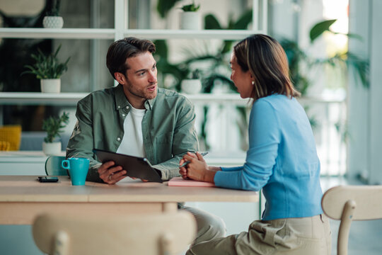 Two diverse professionals collaborating during an office meeting, discussing strategies and communicating effectively