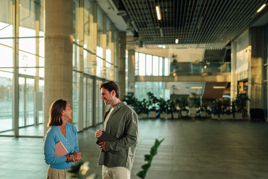 Business colleagues collaborating and discussing ideas in modern office building lobby, sharing knowledge
