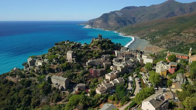 Nonza perched cliff village Corsica cinematic drone flythrough reveal to empty black pebble beach Genoese tower turquoise sea waves Cap Corse landscape