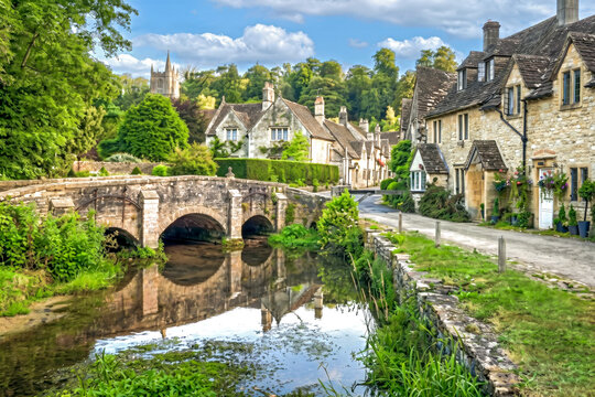 Idyllische Ansicht des historischen Dorfes Castle Combe in England mit einer alten Steinbr&uuml;cke &uuml;ber den Fluss By Brook, traditionellen Steinh&auml;usern und &uuml;ppiger gr&uuml;ner Landschaft.