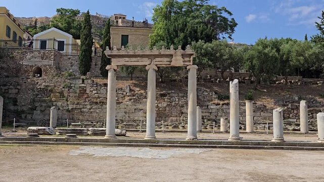 Athens, Greece - 4 July 2026. The Roman Agora contains marble columns, a restored Ionic colonnade and ancient paving, bordered by trees and buildings.