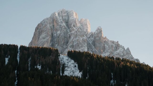 Snowy mountain peak dominates the clear sky. Dense coniferous forest stretches across the foreground. Each keyframe reveals different angles of the alpine landscape