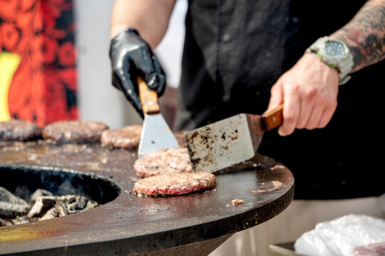 Chef flips patty with spatula over hot griddle