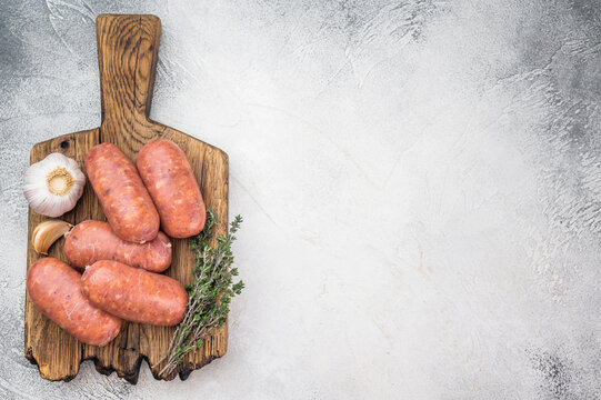 Uncooked pork sausages made from minced meat in natural casing served on cutting board