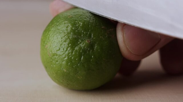 Macro lemon being sliced and dropped slow motion knife lime cutting