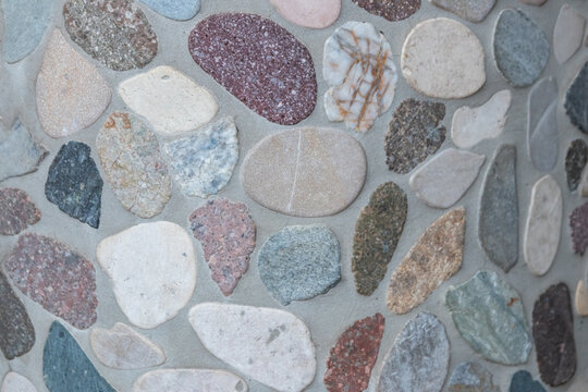 Elegant pebble background with river pebbles decorative wall design in concrete. Modern home decor with natural colorful pebbles as outdoor wall decoration as decorative mosaic with small stones