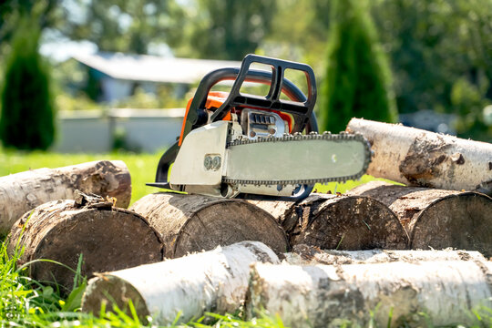 Bright chainsaw rests among stacked logs