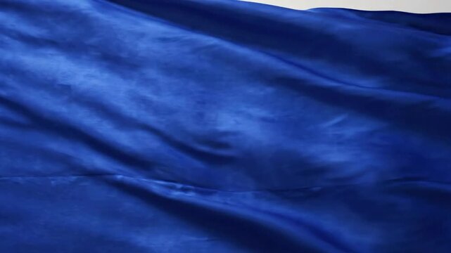 Deep blue silk fabric waving in slow motion, satin textile background, flowing texture