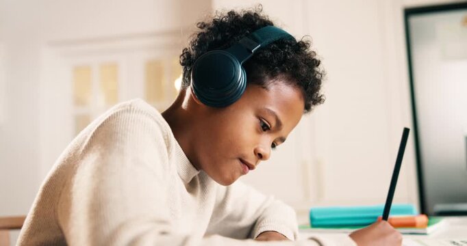 Child, headphones and writing in home with homework, learning critical thinking and listen to music. Boy, study and taking notes in house with school assignment, education and audio tech for song.