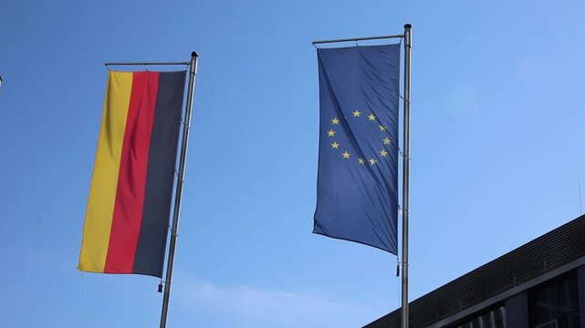 Waving flags from European Union and Germany a on blue sky background show european and germany represented by Germany flag and European Union flag as partners both flags as set