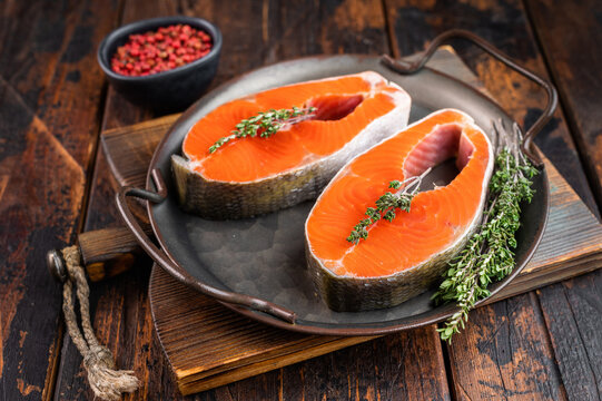 Raw coho salmon steaks also known pink salmon on metal pan over rustic wooden background with copy space