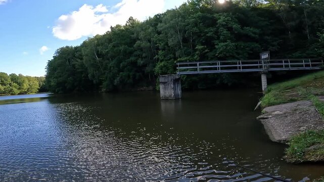 First person POV angler casting spinning rod on a reservoir near concrete bridge. Spin fishing for predatory pikeperch (Sander lucioperca).