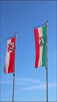 Waving flags from dusseldorf and northrhine westphalia on blue sky background show european and german represented by dusseldorf flag and northrhine westphalia flag as vertical video both flags as set