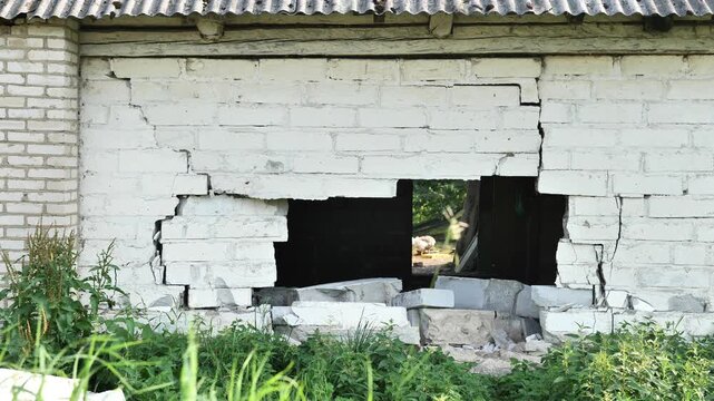 Abandoned brick building with large hole and visible cracks, decaying structure