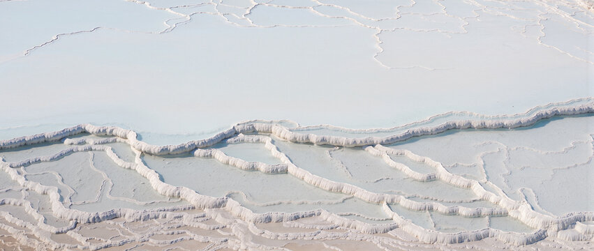 White mineral layers of travertine terraces. Natural thermal pools with turquoise water. Pamukkale geological formation