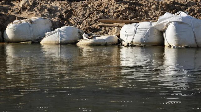 Sandbags protecting riverbank from rising water, preventing flood damage