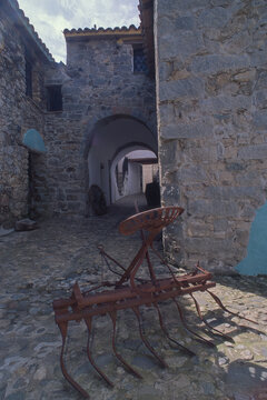an antique rusty metal cultivator or field tiller with tines and a seat, often used as a rustic garden ornament. Bitti, Nuoro, Sardegna. Italia
