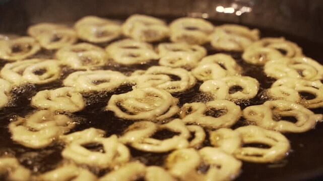 Piping hot jalebis are being fried in oil in the pan.