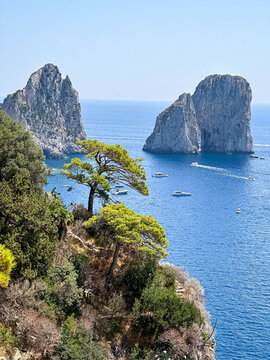 Scenic Coastline View of Faraglioni Rock Formations in Capri, Italy. A panoramic, high-angle view of the iconic Faraglioni sea stacks towering over the deep blue waters of the Mediterranean Sea. The s