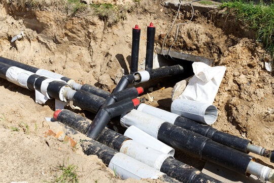 Insulated heating pipes with protective casing  in an open sand trench. Municipal utility replacement, pipeline installation,