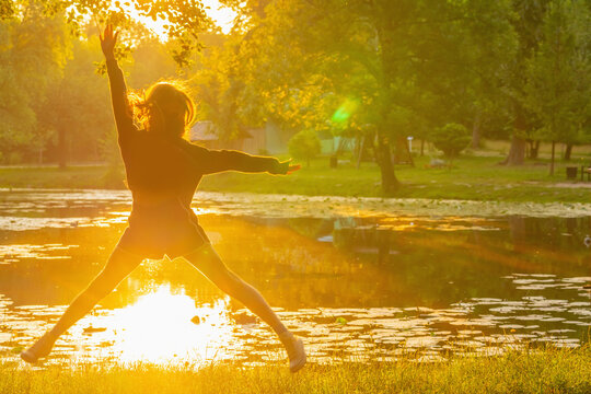 Energetic teenager jumping with arms outstretched during a beautiful sunrise. Copy space for text or design.