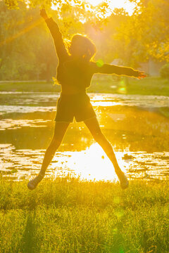 Teenage girl jumping with joy at sunrise &mdash; freedom, happiness, energy and optimism.