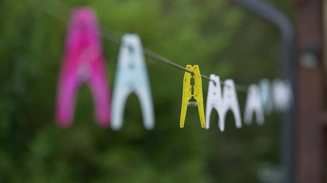 Plastic Clothespins Hanging on Outdoor Clothesline Close Up