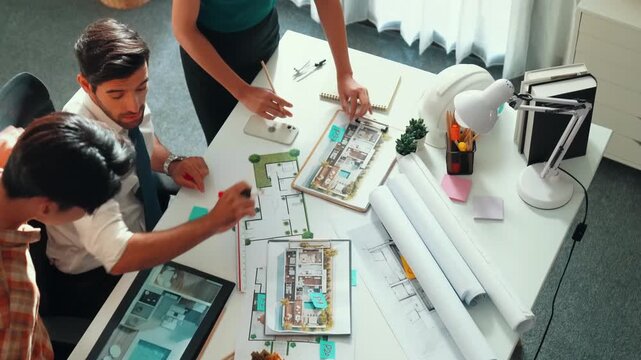 Top view of professional architect engineer team writing sticky notes and sticking note at meeting table while interior designer talking and discussing about building exterior designing. Alimentation.