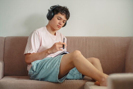 Teenage boy absorbed in writing with headphones on