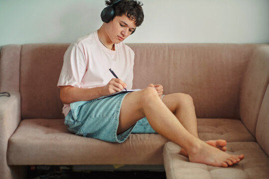 Teenage boy taking notes in a notebook at home