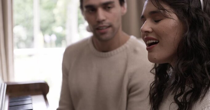 Happy couple, singing and play piano at Christmas celebration party at home. Smile, man and woman on instrument for xmas carols song, music and love for bonding on festive holiday event together