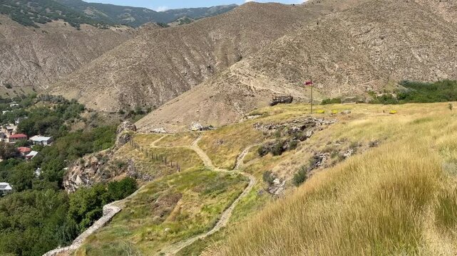 Scenic perspective of Bjni Fortress in Armenia, highlighting the hills, winding pathways, and vibrant greenery in the landscape