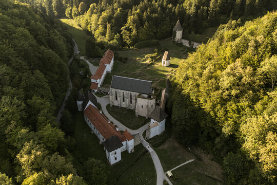 Elevated aerial view of the historic Žiče Charterhouse (Žička kartuzija) monastery complex nestled in a forested valley near Slovenske Konjice, Slovenia