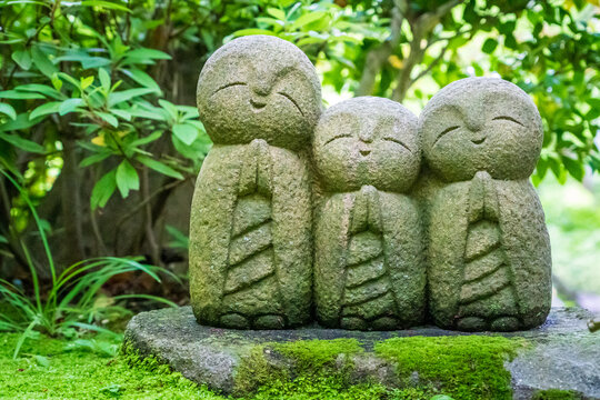 Adorables estatuillas de Monjecitos budista rezando en un jard&iacute;n verde