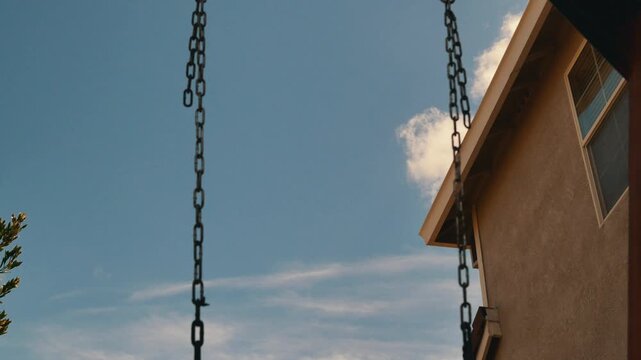 Time lapse of clouds passing behind swing set chains outdoors