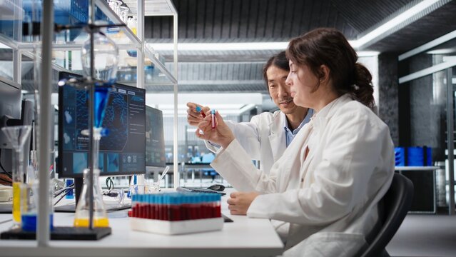 Senior laboratory expert and trainee analyze a batch of blood samples for disease research and clinical testing, while the lab manager and intern examine blood sample vials for further testing.