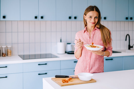 Smiling Woman Eating Healthy Breakfast in Modern Home Kitchen Conveying Wellness and Morning Routine