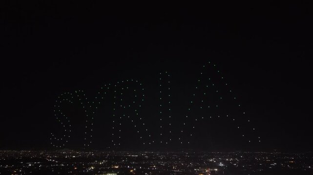 Aerial drone view of a spectacular drone light show spelling the word Syria at night. Illuminated drones forming glowing letters in the dark sky. Aerial entertainment celebrating Syrian heritage. Nigh